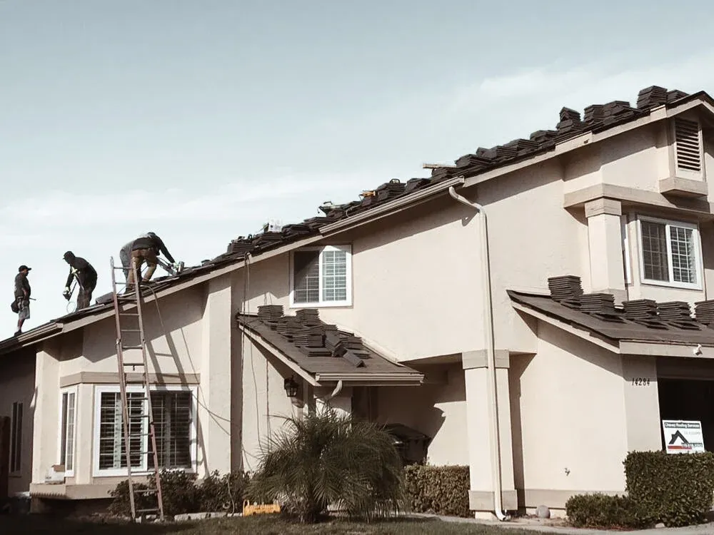Chavez Roofing crew installing shingles on a two-story home