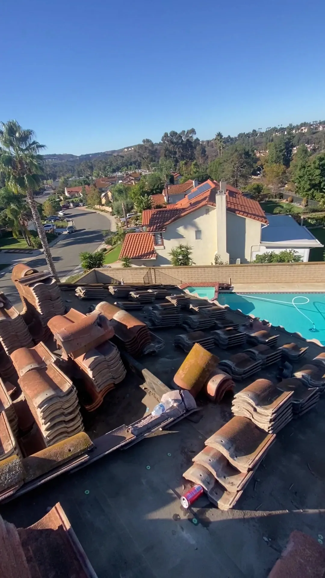 Roof tile stacked and ready on a hillside home with a pool